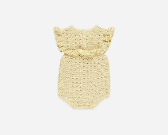 A pale yellow crocheted baby romper with ruffled shoulder straps, displayed flat against a light gray background.