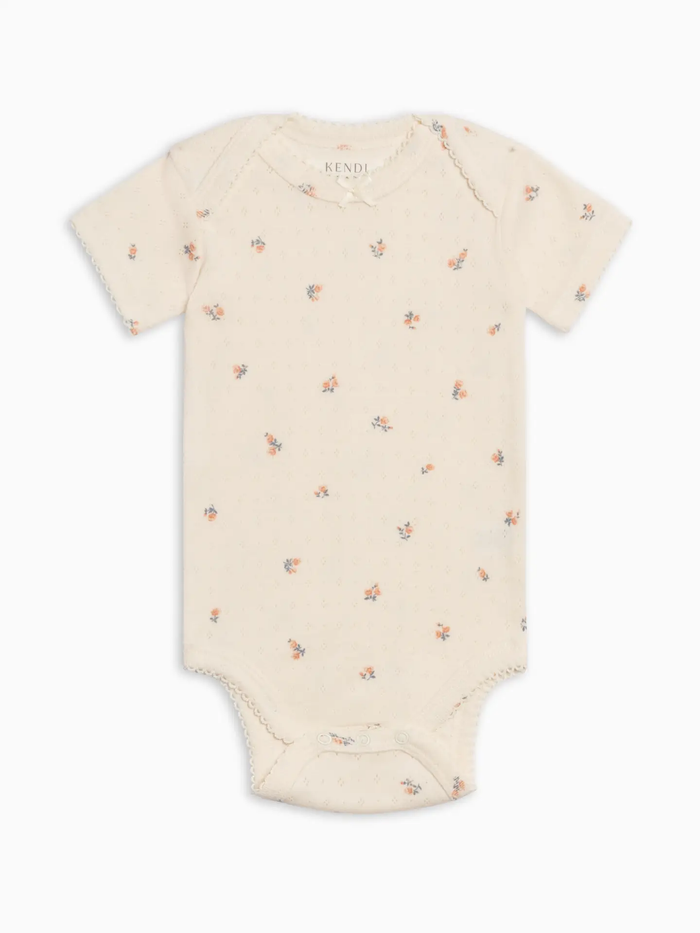Beige baby onesie with small floral pattern on a white background