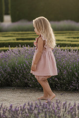 Young girl in a pink dress standing in a room with neutral decor.