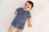 Baby wearing a blue romper with a visible brand logo on a white background