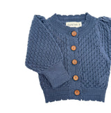 Blue knitted cardigan with brown buttons on a white background