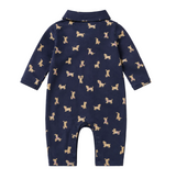 A navy blue baby romper with a repeating pattern of small tan dogs, shown flat against a light cream background.