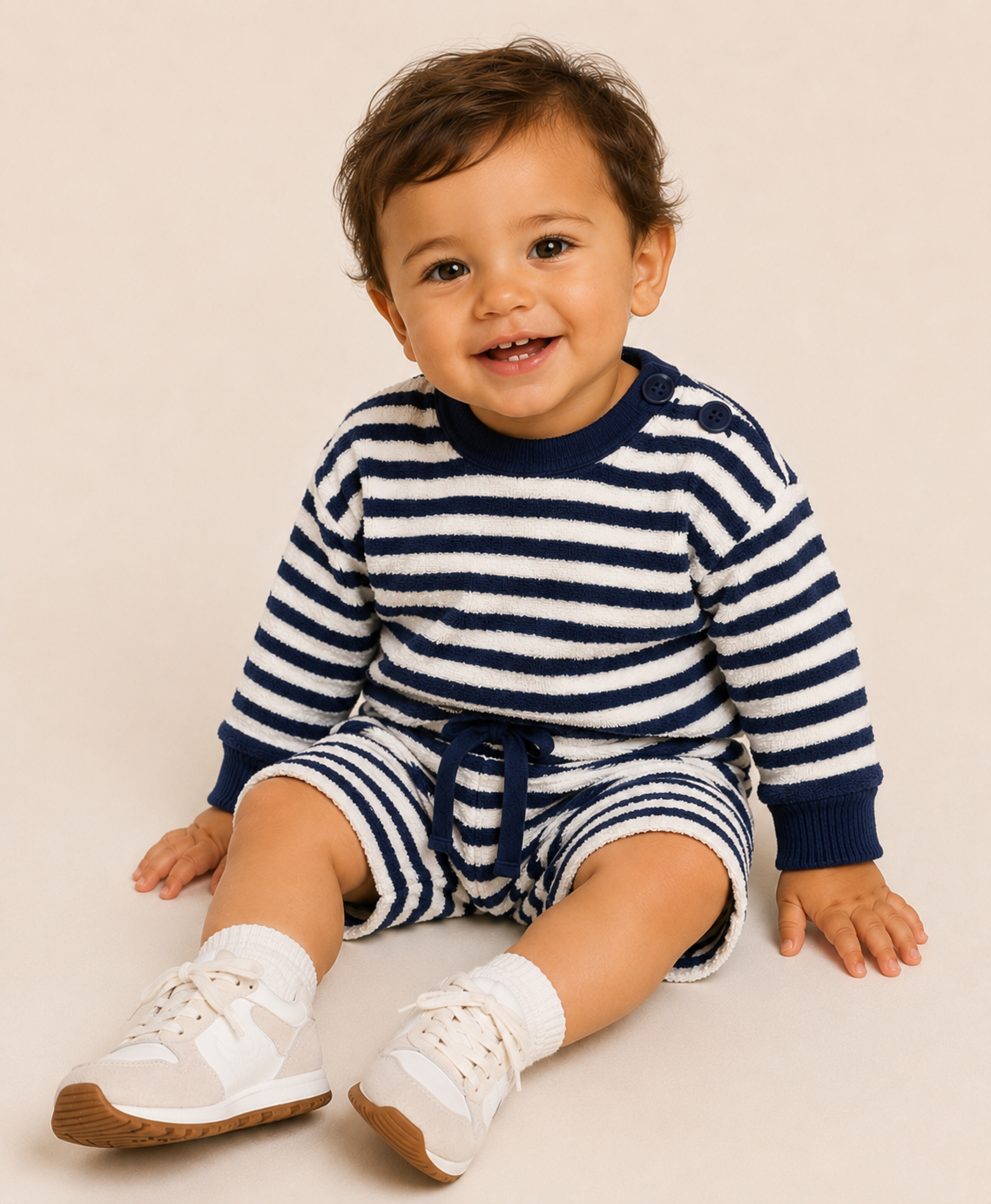 Baby wearing a striped outfit with navy and white colors on a beige background