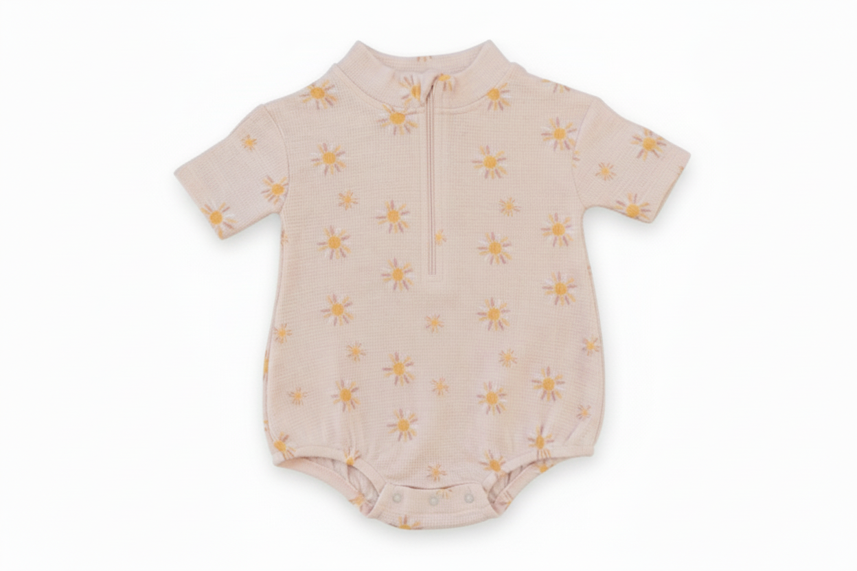 Baby romper with yellow sun patterns on a white background