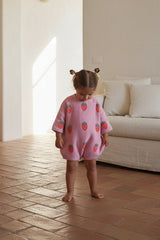 Child wearing a pink outfit with strawberry patterns in a home setting