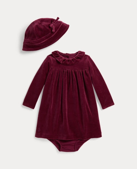 A baby clothing set featuring a long-sleeve dress and a matching bonnet in deep burgundy velvet, displayed on a light gray background.