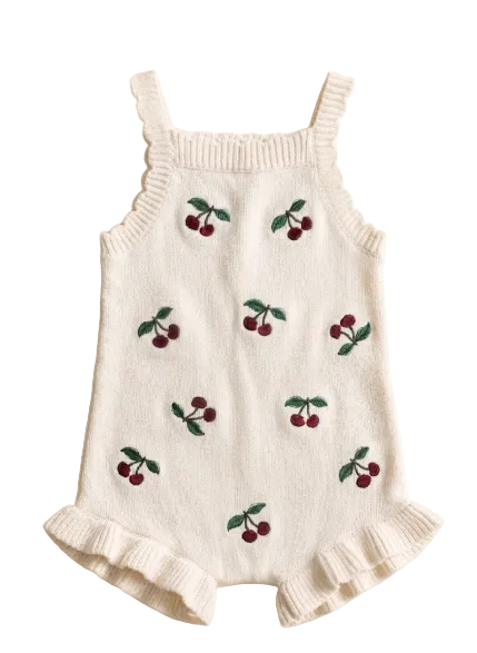 White romper with cherry embroidery on a beige background