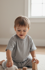 Boy toddler playing with blocks on a light-colored floor in cotton matching set